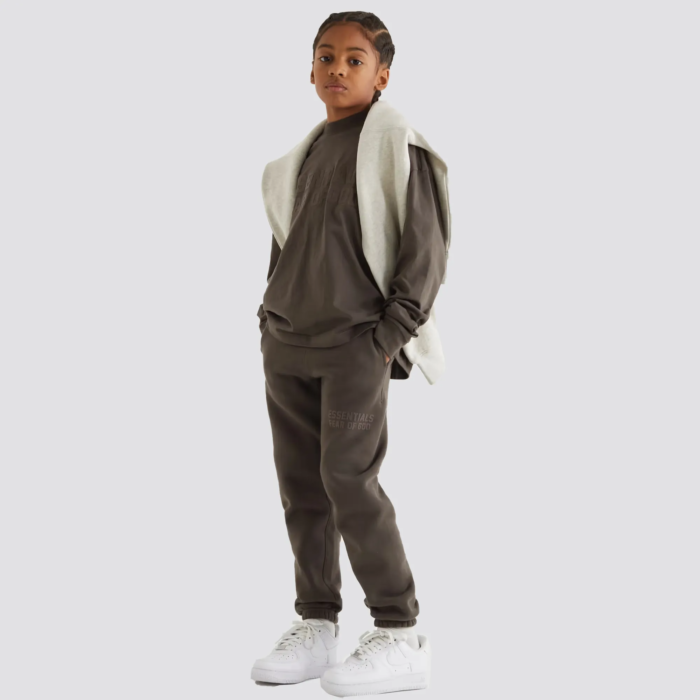 The Fear of God Essentials Kids Tracksuit Logo-Flocked Cotton is a stylish and comfortable tracksuit set for children. It is made by Fear of God, a luxury fashion brand known for its street-inspired and casual designs. The tracksuit is crafted from a soft and comfortable cotton material, and features a flocked logo on the chest and pant leg. The tracksuit includes a full-zip hoodie and pants with ribbed cuffs and hem for a snug fit. The tracksuit comes in a variety of colors, and it's perfect for everyday wear and can be paired with various types of sneakers.